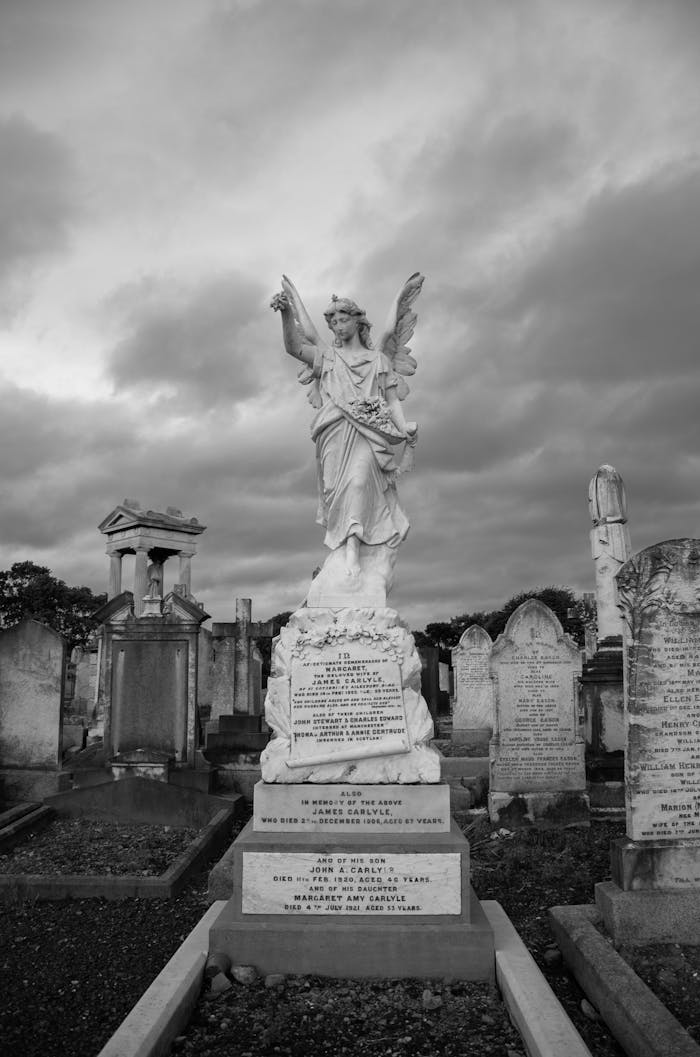 Peaceful black and white photo of a cemetery featuring a striking angel sculpture amid gravestones.
