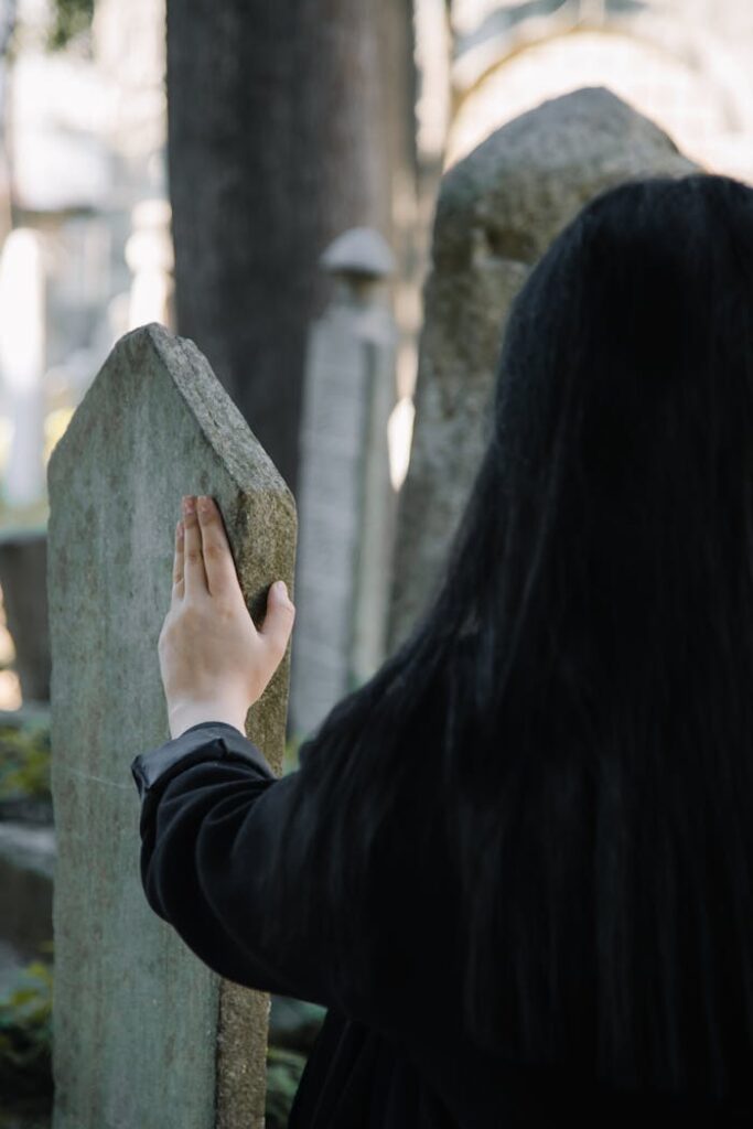 The Art of Drawing Readers In: Your attractive post title goes here Back view of faceless female in black clothes touching old stone gravestone while spending time on cemetery on blurred background