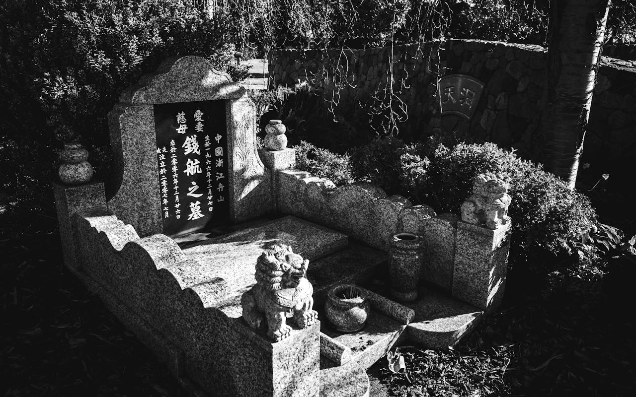 A detailed black and white photograph of a traditional Chinese gravestone with intricate engravings.